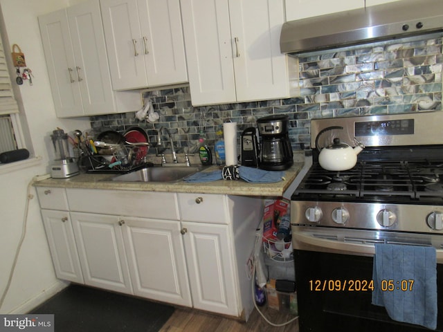 kitchen featuring ventilation hood, dark wood-type flooring, sink, white cabinets, and stainless steel range with gas stovetop