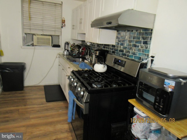 kitchen featuring dark hardwood / wood-style flooring, gas stove, extractor fan, sink, and white cabinets