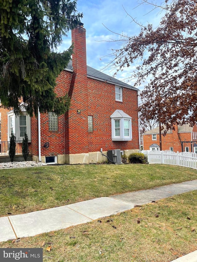 view of property exterior with central AC and a lawn