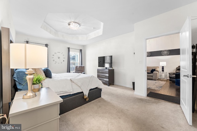 bedroom with light colored carpet and a tray ceiling