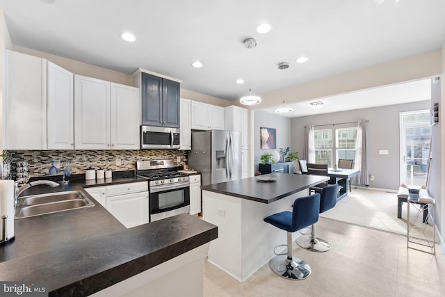 kitchen featuring decorative backsplash, appliances with stainless steel finishes, a kitchen breakfast bar, sink, and white cabinets