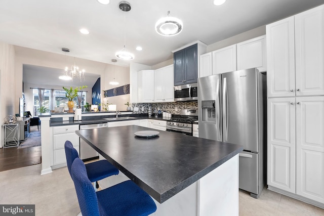 kitchen with hanging light fixtures, kitchen peninsula, lofted ceiling, a breakfast bar area, and appliances with stainless steel finishes