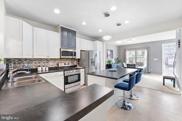 kitchen with sink, decorative backsplash, a breakfast bar, white cabinets, and appliances with stainless steel finishes