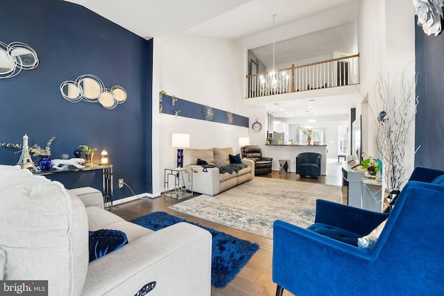 living room with hardwood / wood-style floors, an inviting chandelier, and high vaulted ceiling