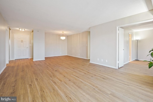 unfurnished room with light wood-type flooring and baseboards