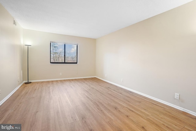 unfurnished room featuring baseboards, visible vents, and light wood-style floors