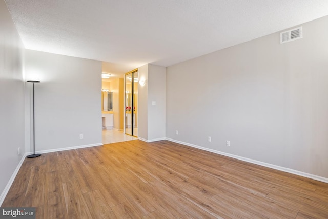 unfurnished room with light wood-style floors, visible vents, and baseboards