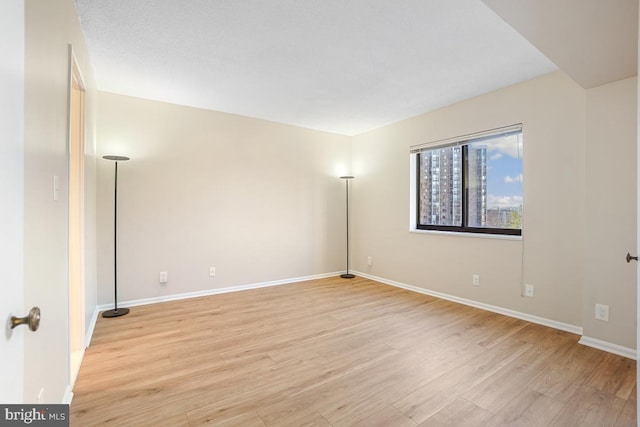 empty room with baseboards and light wood-style floors