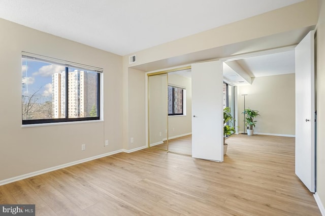 spare room with baseboards, visible vents, and light wood-style floors