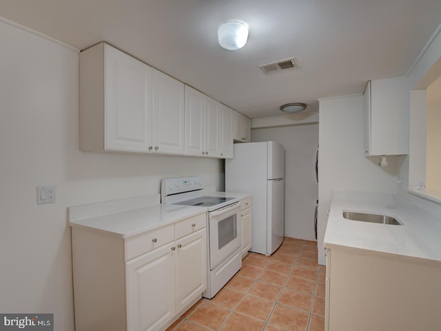 kitchen with white cabinets, light tile patterned flooring, white appliances, and sink