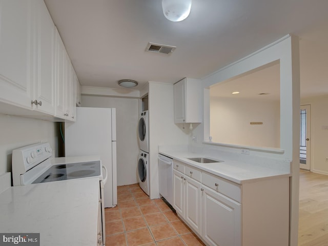 kitchen featuring white cabinets, electric range, dishwasher, and stacked washing maching and dryer