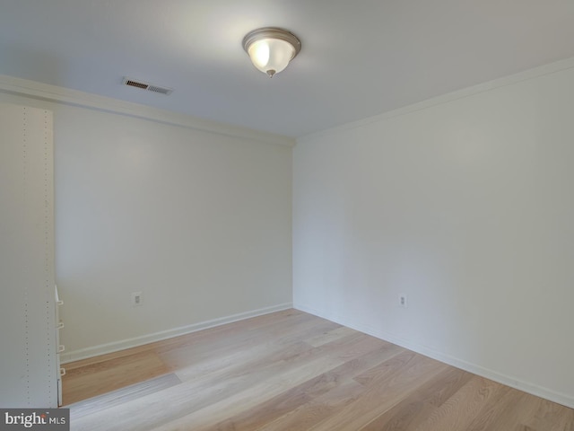 spare room featuring light wood-type flooring and crown molding