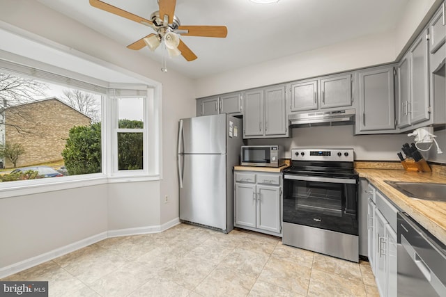 kitchen with gray cabinets, appliances with stainless steel finishes, sink, light tile patterned floors, and ceiling fan