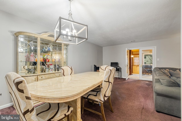 dining area with a textured ceiling, a notable chandelier, and dark carpet