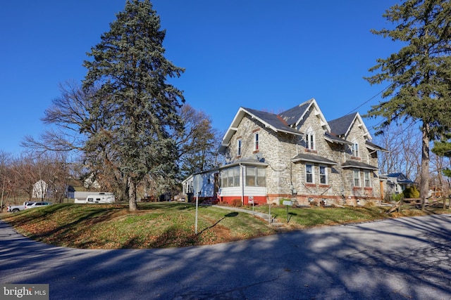 view of property exterior featuring a sunroom and a yard