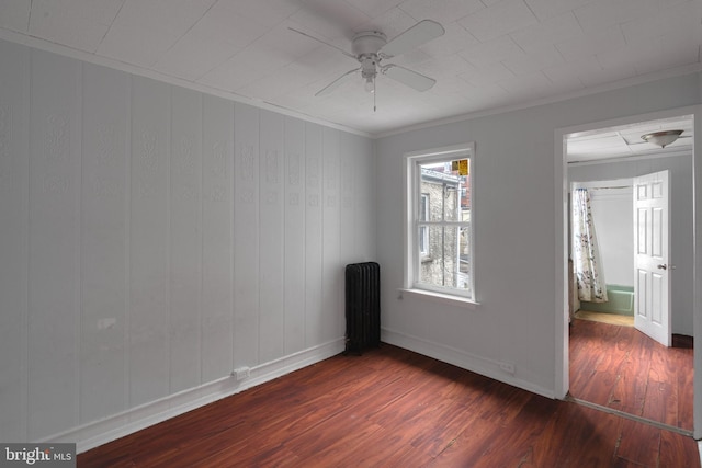 empty room featuring ceiling fan, dark hardwood / wood-style flooring, ornamental molding, and radiator