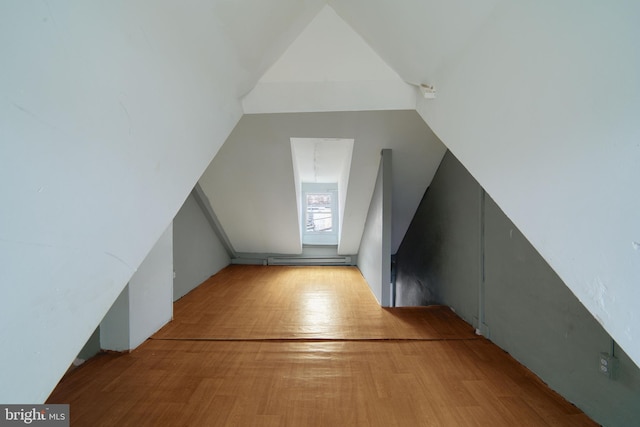 additional living space featuring vaulted ceiling and light wood-type flooring