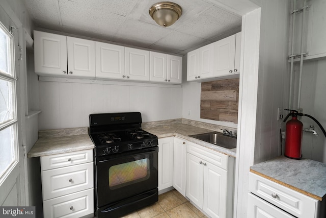 kitchen featuring white cabinetry, wooden walls, plenty of natural light, and black range with gas cooktop