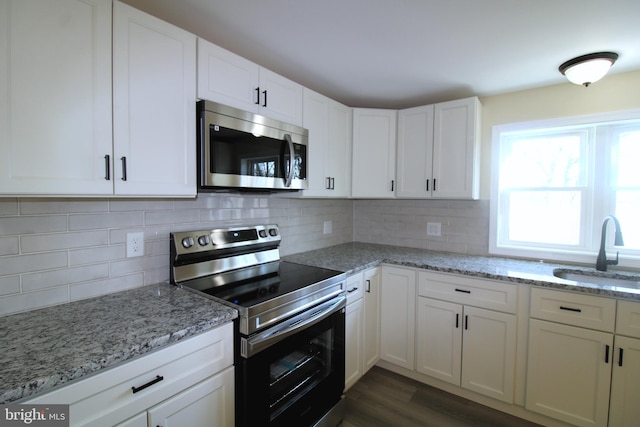 kitchen featuring light stone countertops, sink, dark hardwood / wood-style floors, white cabinets, and appliances with stainless steel finishes