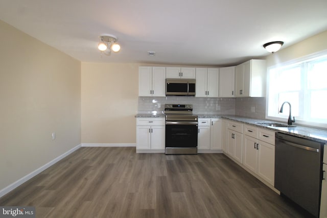 kitchen with light stone countertops, dark hardwood / wood-style flooring, white cabinets, and stainless steel appliances