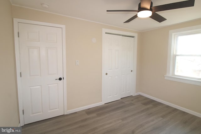 unfurnished bedroom featuring hardwood / wood-style floors, a closet, and ceiling fan