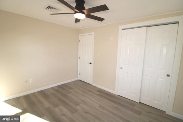 unfurnished bedroom featuring crown molding, ceiling fan, a closet, and wood-type flooring