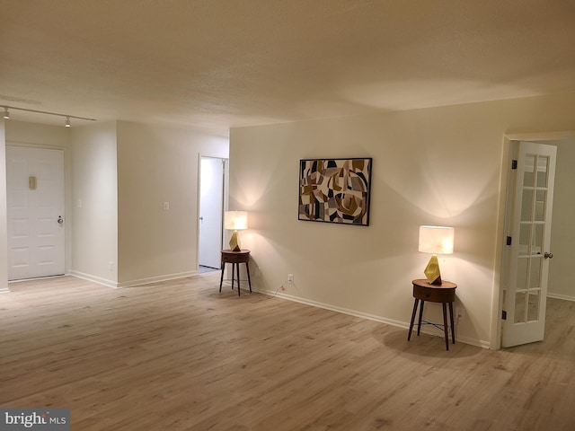 unfurnished room with a textured ceiling, light hardwood / wood-style flooring, and track lighting