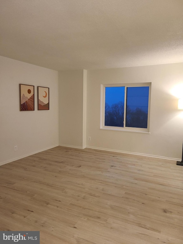 spare room with a textured ceiling and light hardwood / wood-style floors