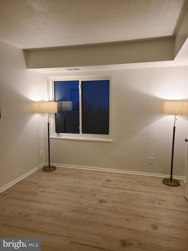 empty room featuring hardwood / wood-style flooring and a textured ceiling