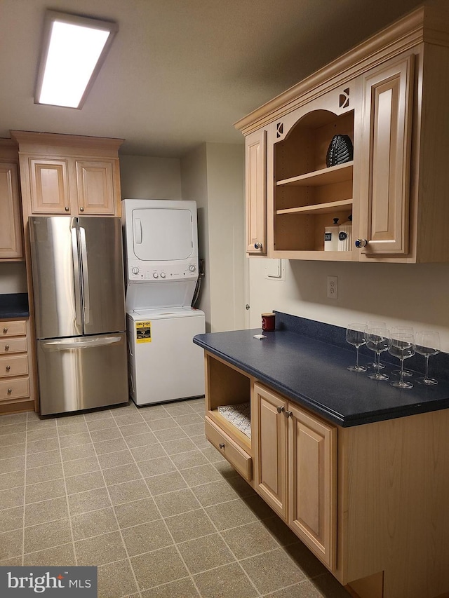 kitchen featuring stainless steel fridge, stacked washing maching and dryer, and light brown cabinets