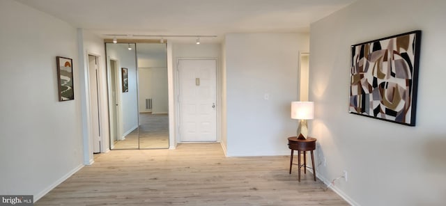 hall featuring rail lighting and light hardwood / wood-style flooring