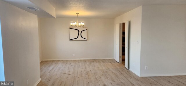 unfurnished dining area with light hardwood / wood-style floors and a notable chandelier