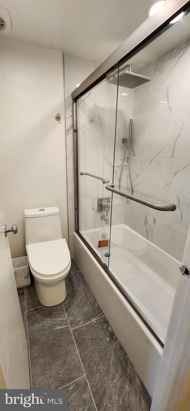 bathroom featuring combined bath / shower with glass door and toilet