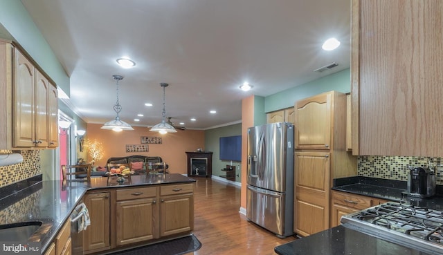 kitchen featuring hardwood / wood-style floors, pendant lighting, backsplash, crown molding, and stainless steel appliances