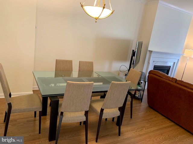 dining space featuring hardwood / wood-style flooring, crown molding, and a fireplace