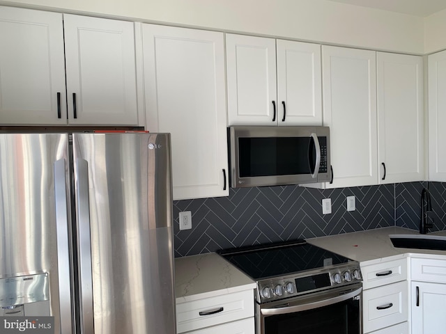 kitchen featuring tasteful backsplash, sink, white cabinets, and appliances with stainless steel finishes