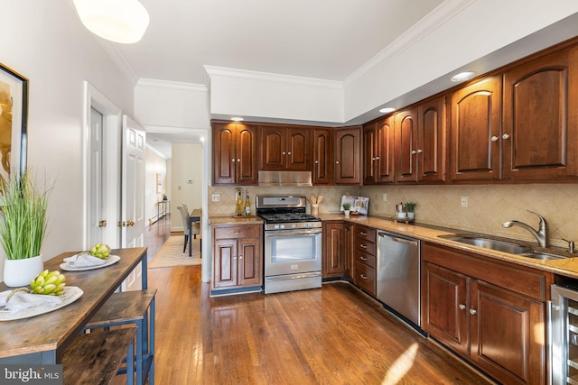 kitchen featuring dark wood-type flooring, sink, ornamental molding, and stainless steel appliances