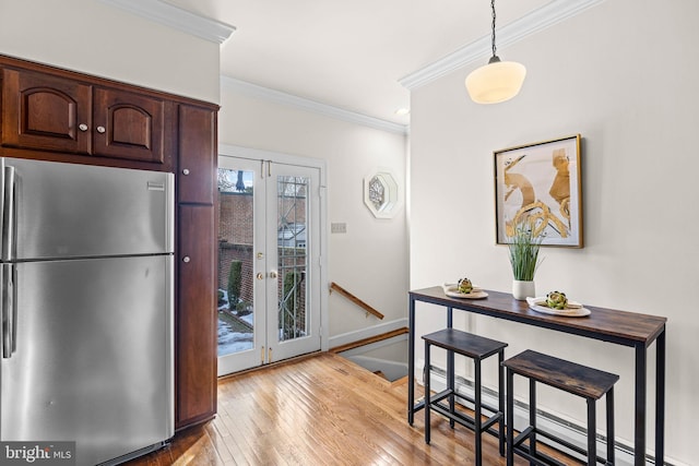 kitchen featuring crown molding, dark brown cabinets, pendant lighting, stainless steel fridge, and light hardwood / wood-style floors