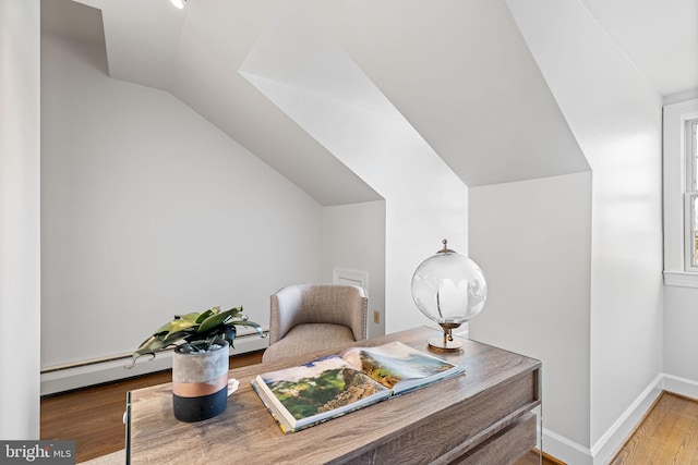 home office with hardwood / wood-style flooring, a baseboard heating unit, and lofted ceiling