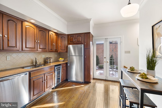 kitchen with tasteful backsplash, sink, pendant lighting, stainless steel appliances, and beverage cooler