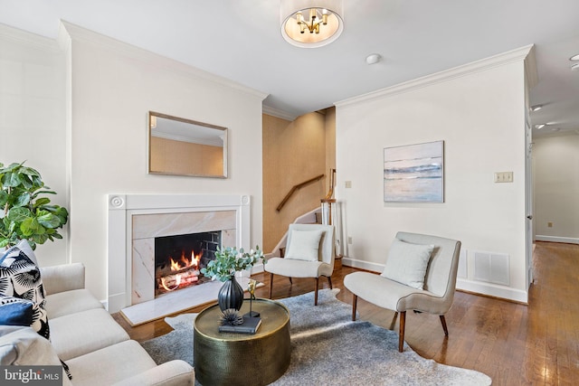 living room featuring hardwood / wood-style floors, crown molding, and a premium fireplace