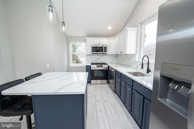 kitchen with blue cabinetry, white cabinetry, sink, vaulted ceiling, and appliances with stainless steel finishes