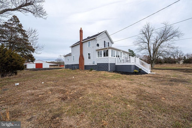 view of side of home with a deck and a lawn