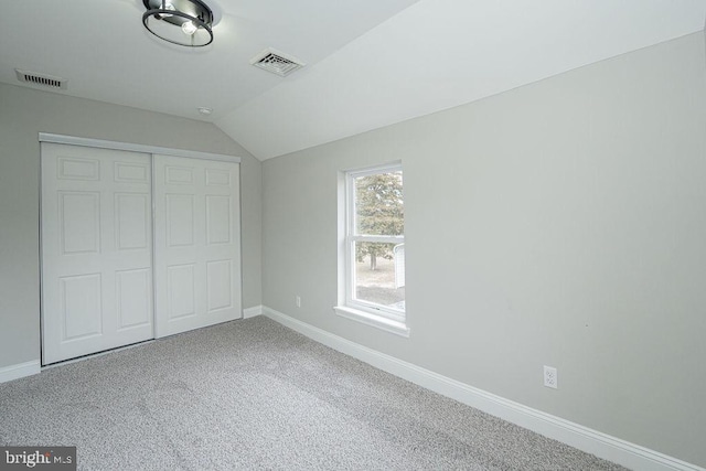 unfurnished bedroom with a closet, carpet floors, and vaulted ceiling