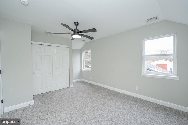 unfurnished bedroom featuring ceiling fan, a closet, carpet floors, and vaulted ceiling