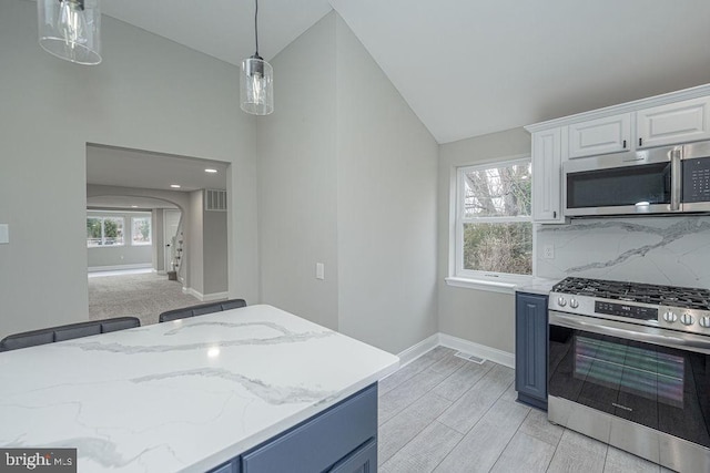 kitchen with white cabinets, stainless steel appliances, vaulted ceiling, and plenty of natural light