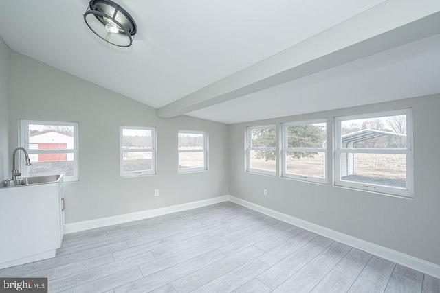 spare room featuring sink, vaulted ceiling, and light hardwood / wood-style flooring