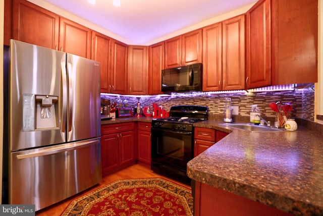 kitchen with black appliances, decorative backsplash, sink, and light hardwood / wood-style flooring