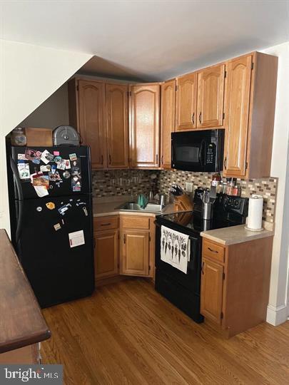 kitchen with black appliances, decorative backsplash, sink, and dark wood-type flooring