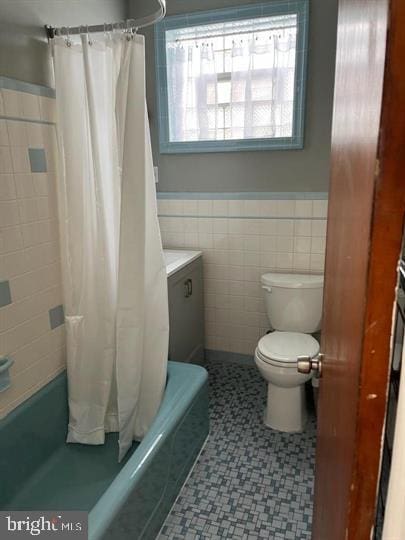 full bathroom with shower / tub combo with curtain, vanity, tile walls, and toilet